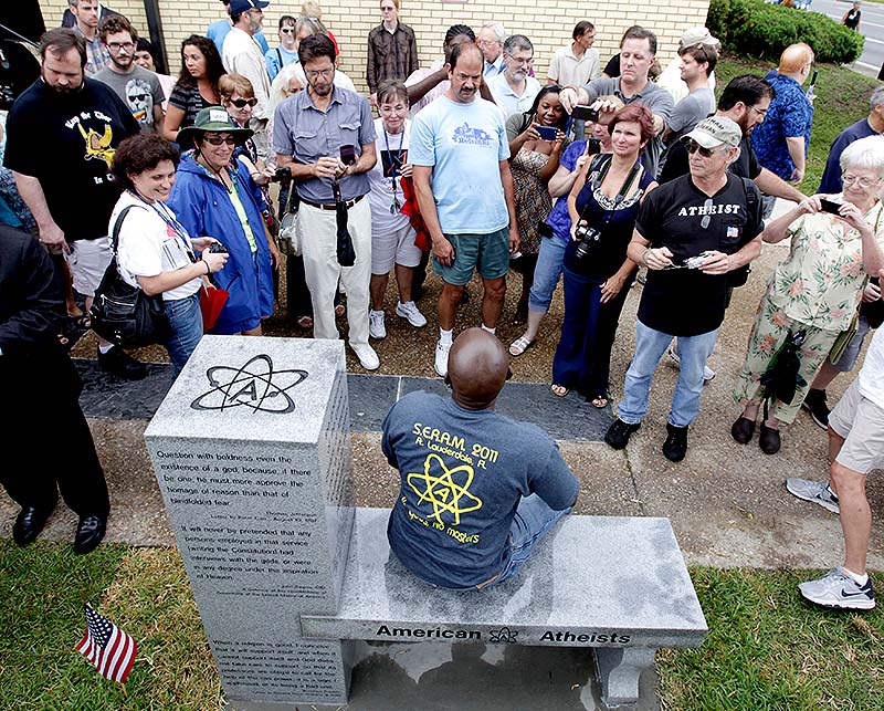 People gather around to sit and take photos during the unveiling of an Atheist monument outside the Bradford County Courthouse on Saturday in Stark, Fla. The New Jersey-based group American Atheists unveiled the 1,500-bound granite bench Saturday as a counter to the religious monument in what's called a free speech zone. Group leaders say they believe it's the first such atheist monument on government property.