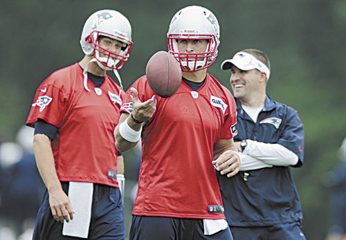 New England Patriots quarterback Tim Tebow, center, tosses the ball as Tom Brady, left, talks with offensive coordinator Josh McDaniels during practice in Foxborough, Mass.