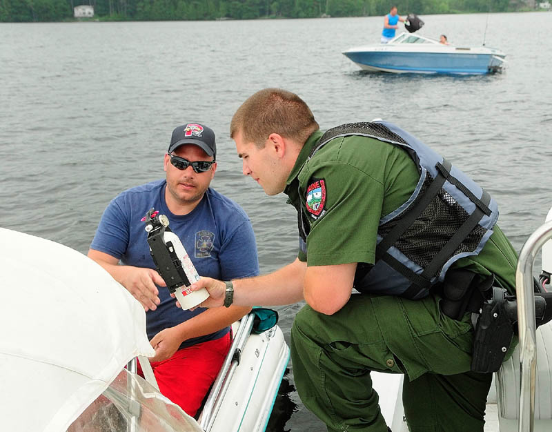 Deputy Game Warden Harry Wiegman checks the fire extinguisher on Steve Sirios' boat while doing a safety check on Wednesday June 26, 2013 on Messalonskee Lake in Sidney. Don't drink and boat – that's the message local, state and federal law enforcement officials want to send when they're patrolling Maine's waters this weekend.