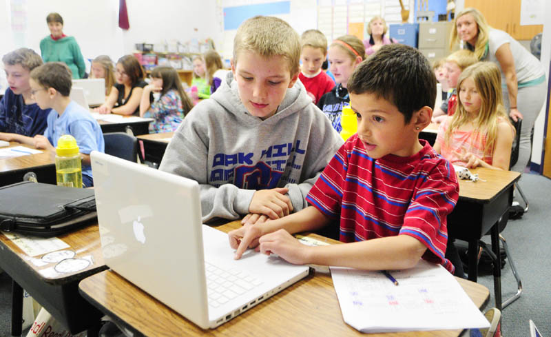 Oak Hill Middle School seventh-grader Eric O'Connor, left, works with a Carrie Ricker School third-grader on an Apple MacBook last month in Litchfield. Maine teachers are overwhelmingly choosing Apple products for their students, the state says.