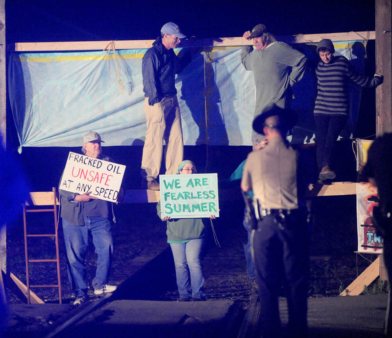 Protesters from a group calling itself 350 Maine erect a barricade on railroad tracks near the Fairfield Town Office on Thursday.