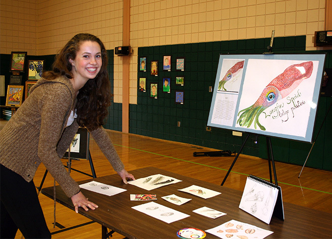 Bree Taylor, a Bonny Eagle High School student, sets up a display of her marine biology artwork for Visual and Performing Arts Night for SAD 6 students.