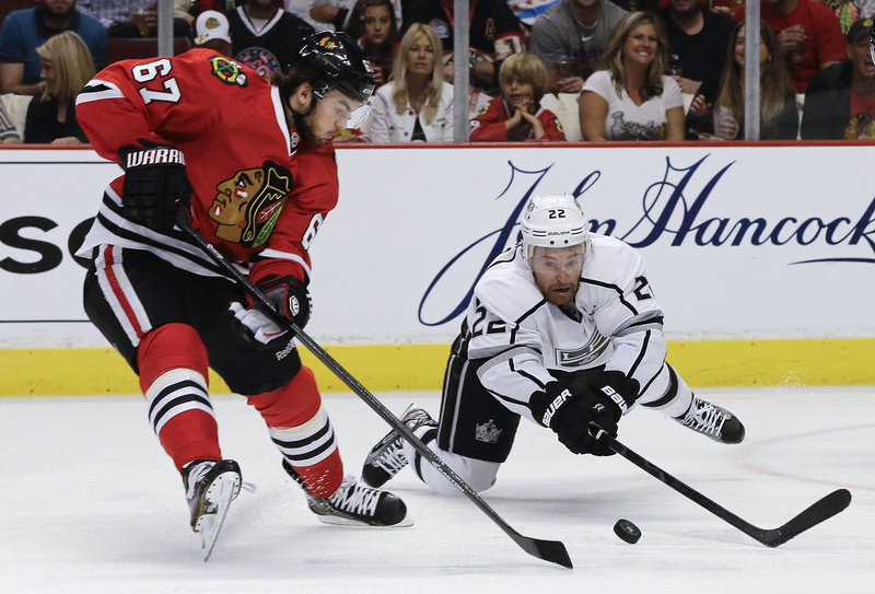Rival forwards Michael Frolik (67) of the Chicago Blackhawks and Trevor Lewis of the Los Angeles Kings scrap for a loose puck during Saturday’s semifinal opener, won by Chicago.