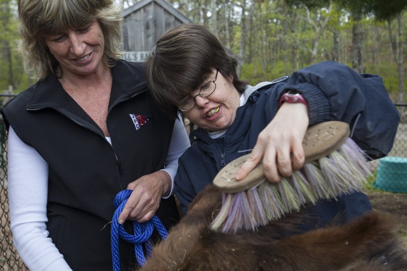 Kris Thompson holds Jake the donkey’s leash as Diane Gaudet brushes his fur during a therapy session. “Donkeys just bring out the best in the residents,” Thompson said.