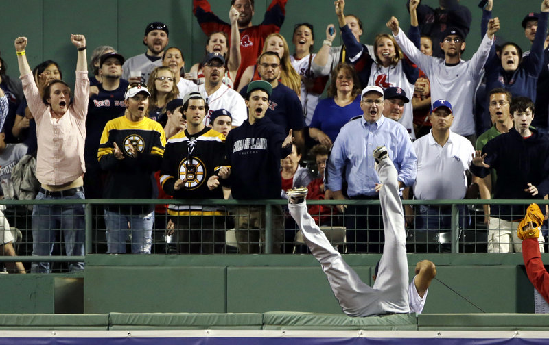 The Rangers’ Nelson Cruz treats the Fenway fans to a major-league effort, as he tumbles headlong over the right-field fence in an attempt to catch a homer by Boston’s Mike Carp.