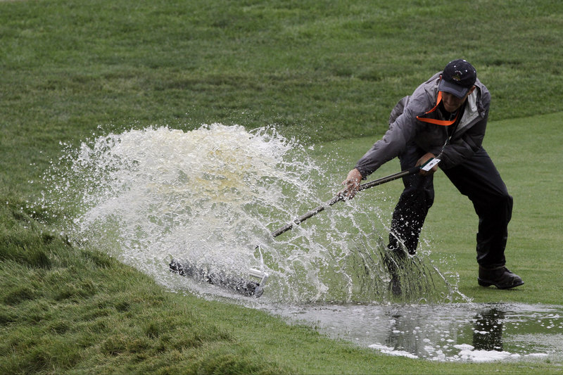 A course worker clears water Monday from the 16th fairway during practice for the U.S. Open golf tournament at Merion Golf Club in Ardmore, Pa.