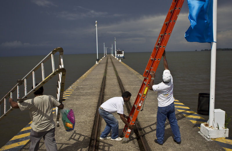 Workers position a ladder to hang a banner on a wharf in Granada surrounded by Lake Nicaragua, which would almost certainly be crossed by the planned canal.