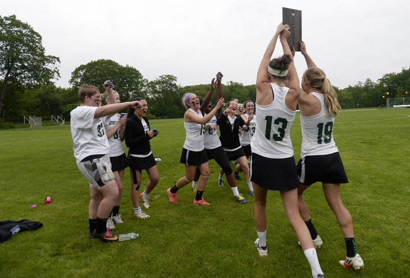 Sadie Cole, 13, and Martha Veroneau of Waynflete carry the regional championship plaque to their teammates after the victory against Cape Elizabeth. Waynflete will meet Yarmouth in the state final Saturday.
