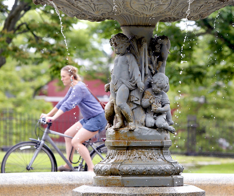A bicyclist rides by the fountain in Lincoln Park in Portland on Thursday. The fountain spire is being reforged and will be placed on the fountain when completed.