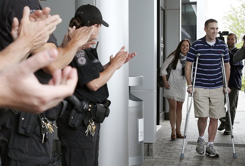 Transit police officer Richard Donohue, front right, leaves Spaulding Rehabilitation Hospital in Boston, followed by his wife Kim, center, Friday, June 14, 2013. Donohue was injured during a shoot-out with the Boston Marathon bombing suspects. (AP Photo/Michael Dwyer)