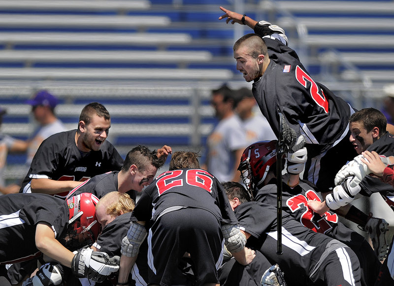 Jurien Garrison, top, jumps onto the pile after Scarborough became the first lacrosse team to win four consecutive state championships since the Maine Principals’ Association started sponsoring the sport in 1998.
