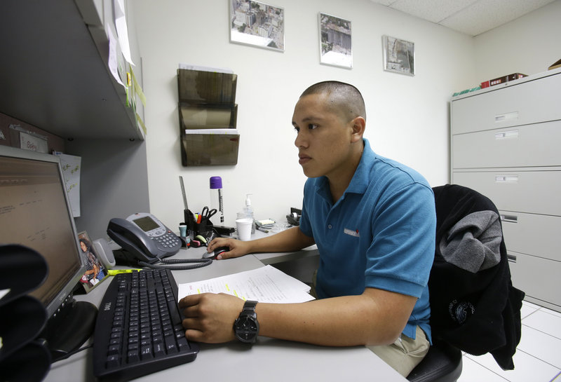 Jorge Tume works on a computer at a concrete company in Miami. Tume’s parents brought him and his younger brother to the U.S. from Peru on tourist visas when they were young.