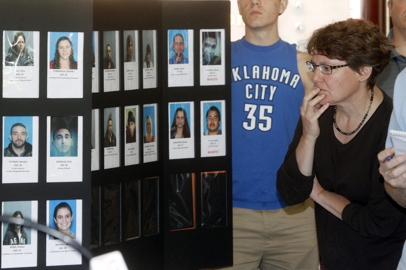 Springfield, Vt., resident Susan White looks over booking photos displayed Wednesday as state police announced the arrests of 33 people in a drug sweep. An increase in heroin traffic statewide prompted this operation and an earlier one that resulted in 47 arrests.