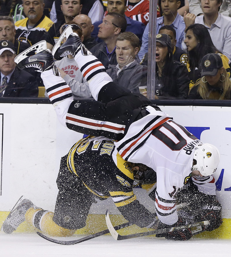 Bruins defenseman Johnny Boychuk upends Chicago's Patrick Sharp along the boards in the third period of Game 4.