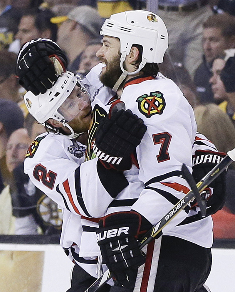 The Blackhawks get to celebrate again in OT as Brent Seabrook, right, embraces Duncan Keith after scoring at 9:51 of overtime Wednesday night at Boston. The Blackhawks’ 6-5 win evens the Stanley Cup finals, 2-2. Chicago won Game 1 in triple overtime.