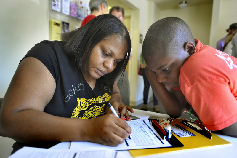The Portland Community Health Center in Portland's Riverton Park, operated by the University of New England, will serve the immigrant, low-income and refugee communities. Isaiah Ntumba, 11, watches his mother Patricia Ntumba fill out patient registration papers at the clinic on Thursday, June 20, 2013.