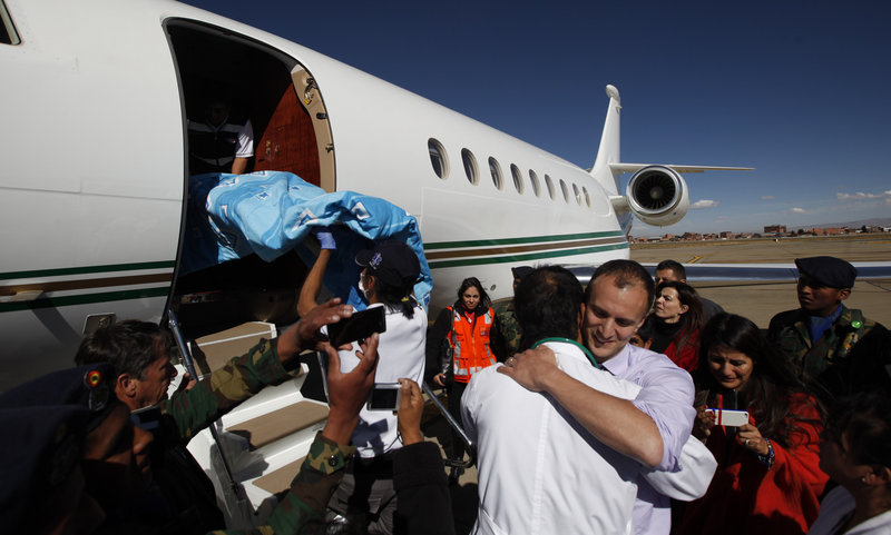 U.S. Dr. Joseph Currier, right, facing camera, embraces a Bolivian doctor, as a stretcher carrying four-year-old Rosalie is placed into a private plane at the airport in El Alto, Bolivia, Thursday, June 20, 2013. Rosalie, who was attacked by a Rottweiler about 4 months ago, came out of her coma and is being transferred to a hospital in Boston for reconstructive face surgery. (AP Photo/Juan Karita)