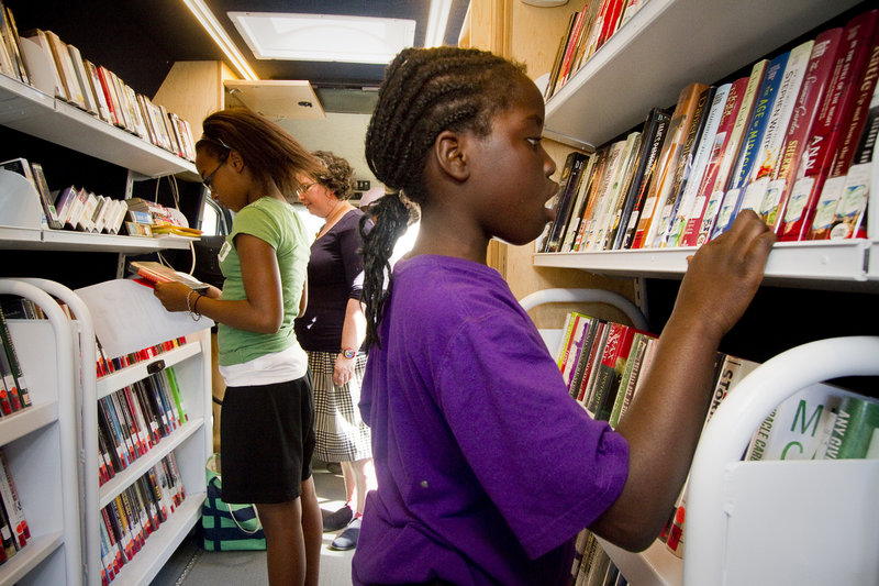 Lina Wakati, 9 of Portland, chooses books from the Portland Public Library's mobile unit in front of The Root Cellar on Washington Avenue in Portland. The mobile unit will make regular visits around Portland throughout the summer, supplying books to kids over the summer vacation.