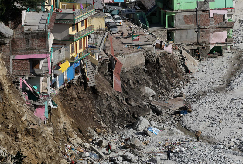 Buildings teeter at the edge of an area eroded by floods and landslides in Govindghat, India. Soldiers were working Saturday to evacuate tens of thousands of people in northern India’s Himalayas, building bridges and opening routes.
