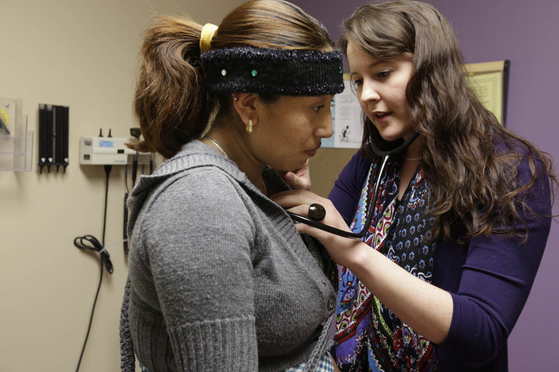Medical resident Stephanie Place examines Maria Cazho at the Erie Family Health Center in Chicago. Since last summer, Place, 28, has received hundreds of emails and phone calls from headhunters, recruiting agencies and health clinics.