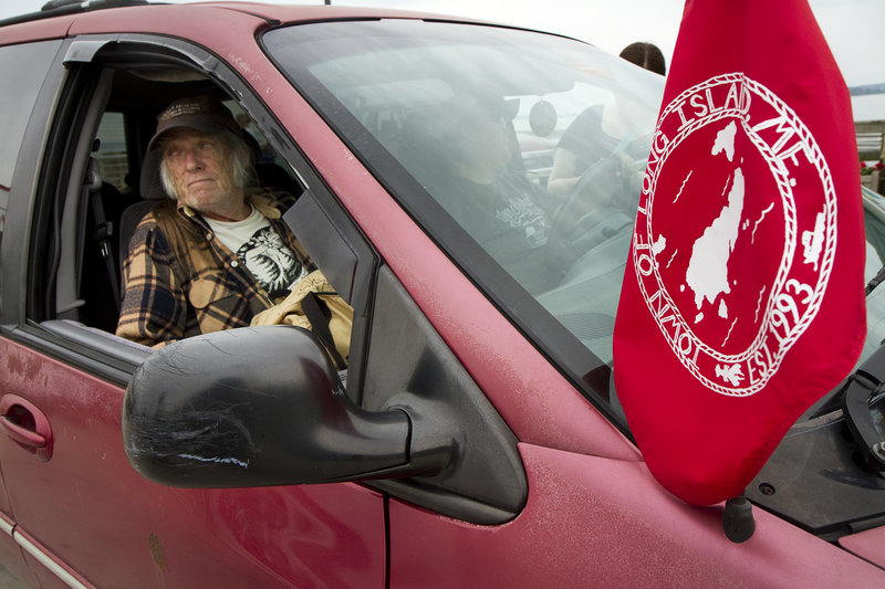 Michael Kilgore sits in the passenger seat of a car displaying the Long Island town flag. The car is owned by island resident Lorinda Vallas.