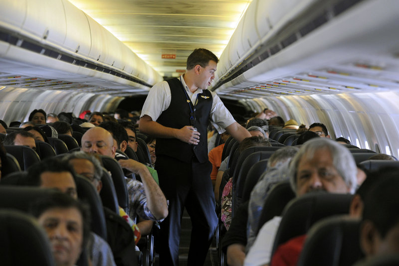 Allegiant Air flight attendant Chris Killian prepares passengers for the flight from Las Vegas to Laredo, Texas. The airline has low fares but tacks on many fees.