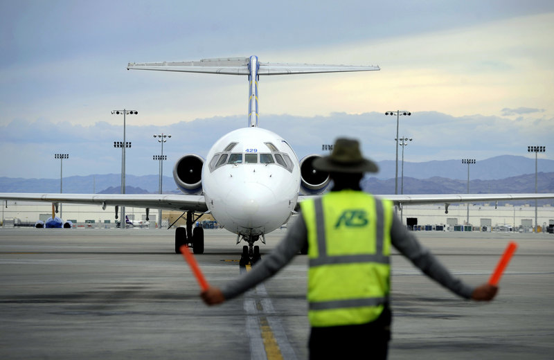 A ground worker guides an incoming Allegiant Air jet at McCarran International Airport in Las Vegas. Allegiant promotes its destinations, rather than itself, to those who seldom fly.