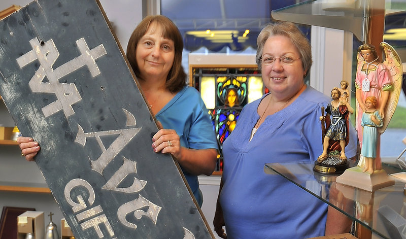 On Friday, Ave Maria Gift Shop owner, Connie Somma, left, and longtime employee Joanne Costa are surrounded by some of the store's iconic merchandise and the sign they took down today. The shop is closing after 65 years.