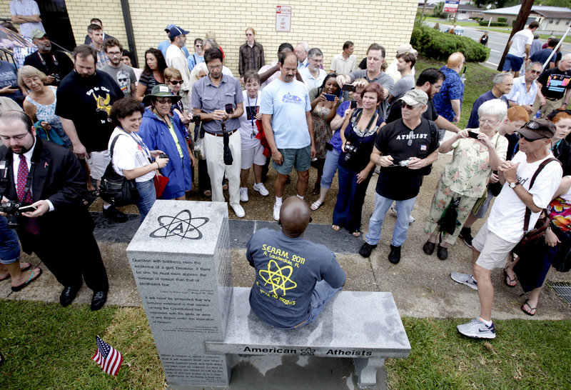 People gather around to sit and take photos during the unveiling of an atheist monument outside the Bradford County Courthouse on Saturday in Stark, Fla.