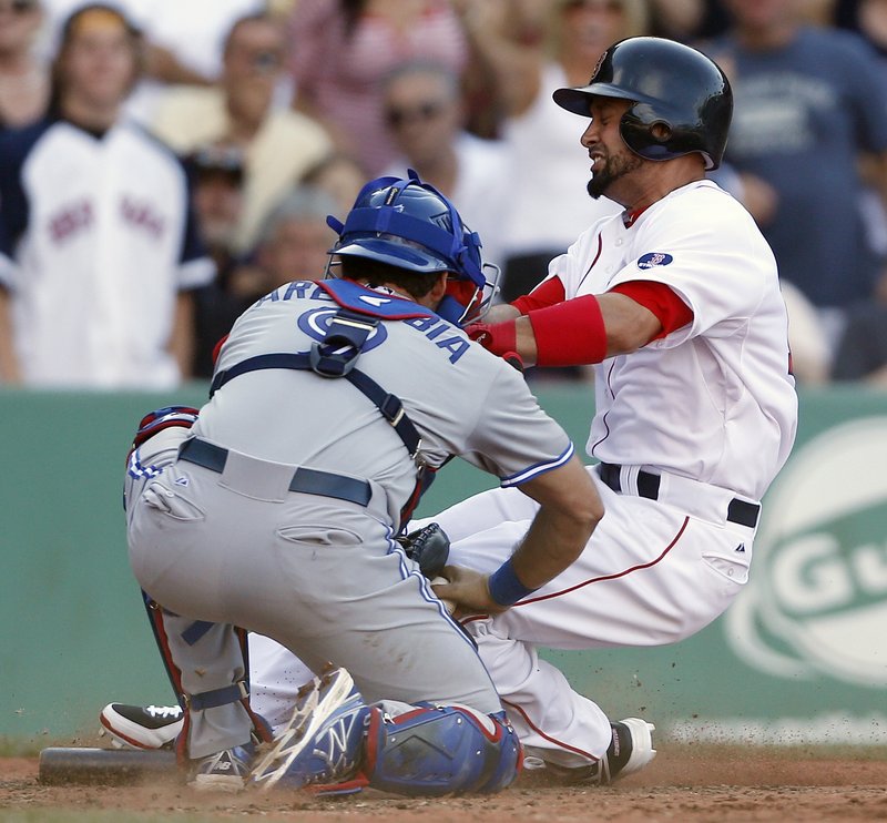 Boston’s Shane Victorino is tagged out at home by catcher J.P. Arencibia after trying to score from second on a single by Dustin Pedroia during sixth-inning action of Saturday’s game at Fenway Park.