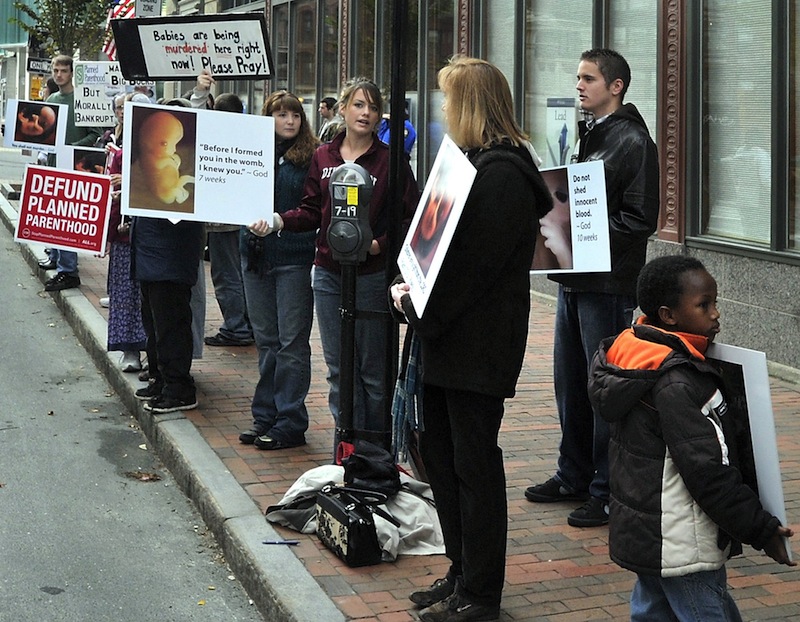 In this October 2012 file photo, anti-abortion demonstrators protest with graphic signs outside the Planned Parenthood of New England agency on Congress Street in Portland, Maine. At a meeting of a City Council subcommittee Tuesday, the Portland Police Department will report on the weekly anti-abortion protests outside Planned Parenthood's clinic on 443 Congress St.