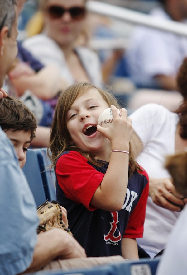 Grey Roessler, 7, of Florence, Mass., shows her dad, Jo, far left, how a baseball that was tossed to her by a Portland Sea Dogs player bonked her on the cheek during Monday's game vs. the New Britain Rock Cats at Hadlock Field in Portland, July 8, 2013. In addition to her dad, Grey was with her mom, Nora, and her twin brother, Gerrit, 7.