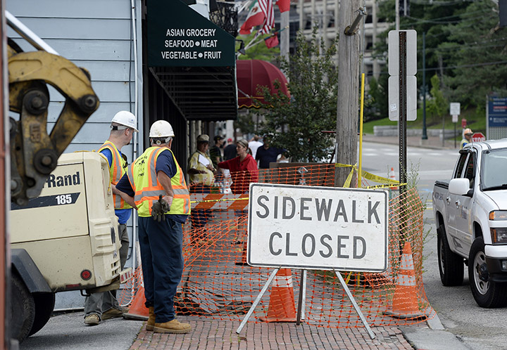 Workers look over a damaged sidewalk on Congress Street after a water main break Monday.