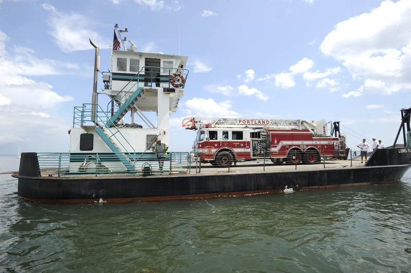 A barge leaves East End Beach in Portland on Wednesday carrying Portland Fire Department's Ladder 12, which has been refurbished and was on its way to Peaks Island.