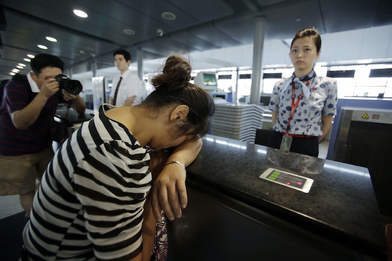 An unidentified family member of the two girls killed during the Asiana Airlines plane crash on Saturday, cries at the Asiana Airlines counter as she and other family members check infer the flight to San Francisco at the Pudong International Airport in Shanghai, China, Monday, July 8, 2013. The Asiana Airlines flight crashed while landing at San Francisco International Airport on Saturday, killing at least two people, injuring dozens of others and forcing passengers to jump down the emergency inflatable slides to safety as flames tore through the plane. The flight originated in Shanghai, China, and stopped over in Seoul, South Korea, before coming to San Francisco, airport officials said. (AP Photo/Eugene Hoshiko)