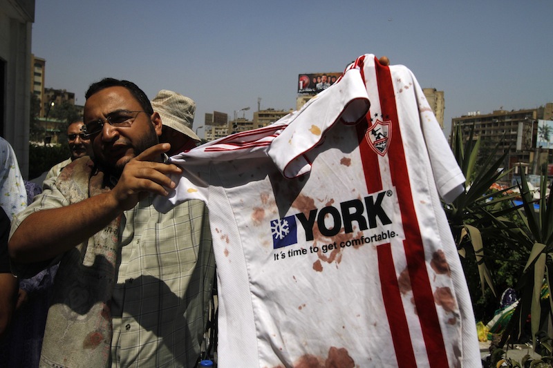 A supporter of ousted Egyptian President Mohammed Morsi stands outside a local hospital in Cairo holding a bloodied shirt he says belongs to a protester shot by soldiers during a demonstration, Monday, July 8, 2013. Egyptian soldiers and police opened fire on supporters of the ousted president early Monday in violence that left dozens of people killed, including one officer, outside a military building in Cairo where demonstrators had been holding a sit-in, government officials and witnesses said. (AP Photo/Nasser Shiyoukhi)