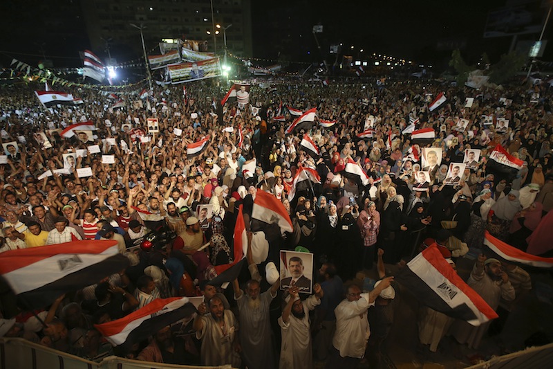 Supporters of the ousted Egypt's President Mohammed Morsi, hold his portraits and wave Egyptian flags as they shout slogans during a demonstration after the Iftar prayer, evening meal when Muslims break their fast during the Islamic month of Ramadan, in Nasr City, Cairo, Egypt, Wednesday July 10, 2013. Egypt's military-backed government tightened a crackdown on the Muslim Brotherhood on Wednesday, ordering the arrest of its revered leader in a bid to choke off the group's campaign to reinstate President Mohammed Morsi one week after an army-led coup. (AP Photo/Hussein Malla)