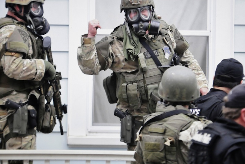 In this Friday, April 19, 2013 Massachusetts State Police photo, state troopers dressed in protective gear hold weapons as they stand near a home, in Watertown, Mass. Later that night, 19-year-old Boston Marathon bombing suspect Dzhokhar Tsarnaev was captured. (AP Photo/Massachusetts State Police, Sean Murphy)