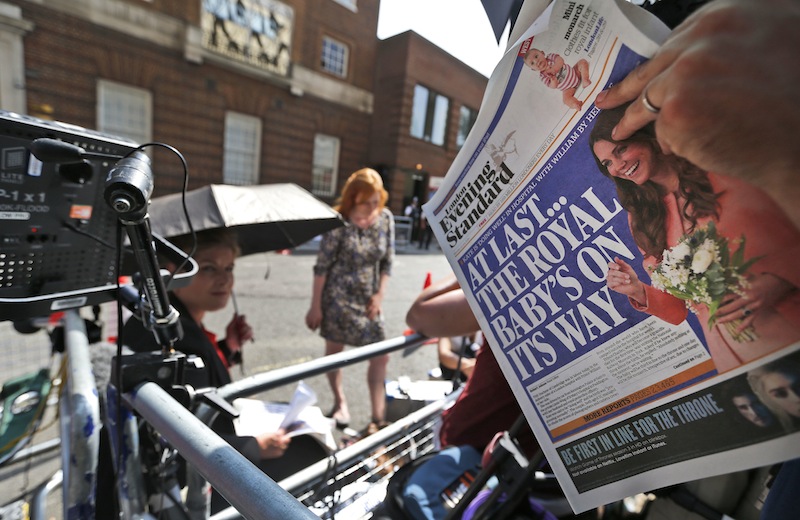 A news cameraman reads a newspaper across from St. Mary's Hospital's exclusive Lindo Wing in London, Monday, July 22, 2013. Buckingham Palace officials say Prince William's wife, Kate, has been admitted to the hospital in the early stages of labor. Royal officials said that Kate traveled by car to St. Mary's Hospital in central London. Kate _ also known as the Duchess of Cambridge _ is expected to give birth in the private Lindo Wing of the hospital, where Princess Diana gave birth to William and his younger brother, Prince Harry. The baby will be third in line for the British throne _ behind Prince Charles and William _ and is anticipated eventually to become king or queen. (AP Photo/Lefteris Pitarakis)