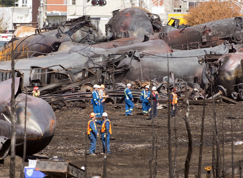 Workers stand before mangled tanker cars Tuesday, July 16, 2013, at the crash site of the train derailment and fire in Lac-Megantic, Quebec. The July 6, 2013, accident left 37 people confirmed dead and another 13 missing and presumed dead. (AP Photo/Ryan Remiorz, pool) Canada Quebec Montreal;transportation;business;Canada;Canadian;economic;economy;industry;move;ship;shipping;transit;transport;travel industry;commerce;tourism;fire;train;rail;derail;tragedy;disaster