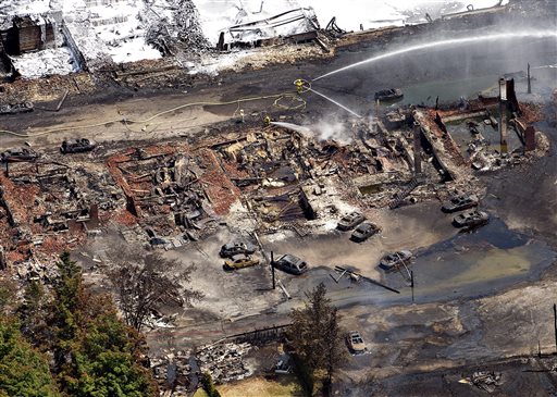 The downtown core lays in ruins as fire fighters continue to water smoldering rubble Sunday, July 7, 2013 in Lac Megantic, Quebec after a train derailed ignited tanker cars carrying crude oil. (AP Photo/The Canadian Press, Paul Chiasson)