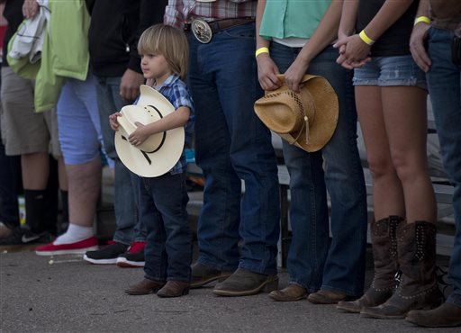 A young boy holds his hat as he and others stand for the national anthem before the start of the Prescott Frontier Days Rodeo, Wednesday in Prescott, Ariz. A mile-high city about 90 miles northwest of Phoenix, Prescott remains a modern-day outpost of the pioneer spirit. It's that spirit that will guide officials as they navigate the days ahead and figure out how to honor the elite Hotshot firefighters who died in a nearby wind-driven wildfire that is still burning. (AP Photo/Julie Jacobson)