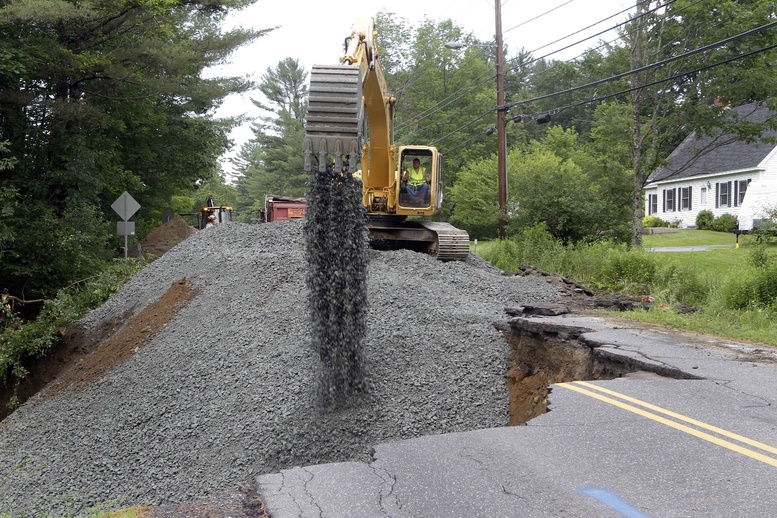 Kevin McNamara works to fill in a washed-out road Wednesday in Lebanon, N.H. Heavy rains caused flash flooding in the region.