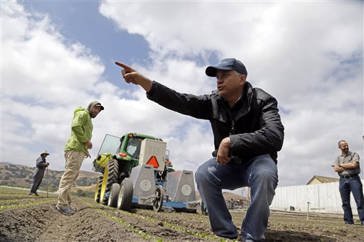 Jorge Heraud, CEO of Blue River Technology, center, explains how the Lettuce Bot works as software engineer Willy Pell, in green, watches in Salinas, Calif., recently. The Lettuce Bot is designed to thin fields of lettuce, a job that now requires detailed hand work by 20 farm workers.