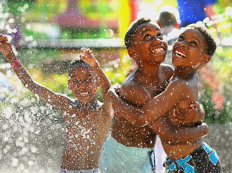 Nine-year-old William Williams, right, hugs his brother Xavier Robertson, 10, while waiting for the Big Splash machine at the Como Town water park to dump water on them in St. Paul, Minn., on Wednesday, when the temperature hit 92 degrees, with a heat index of 97 degrees.