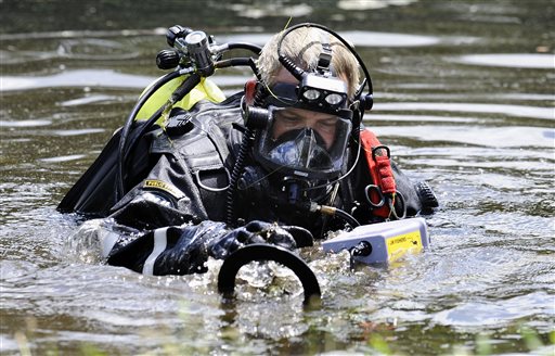 A Connecticut State Police dive team member searches Pine Lake in Bristol, Conn., the hometown of the former New England Patriots player Aaron Hernandez on Monday. Other officers could be seen combing the water's edge.