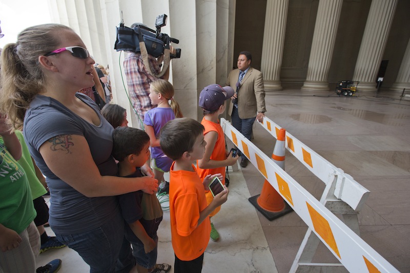 Tourists and reporters stand behind a police barrier as the central hall of the Lincoln Memorial in Washington, Friday, July 26, 2013, as it was closed for cleaning after someone splattered green paint on the statue of the 16th president and the floor area. Police say the apparent vandalism was discovered early Friday morning with no words, letters or symbols visible in the paint. (AP Photo/J. Scott Applewhite)