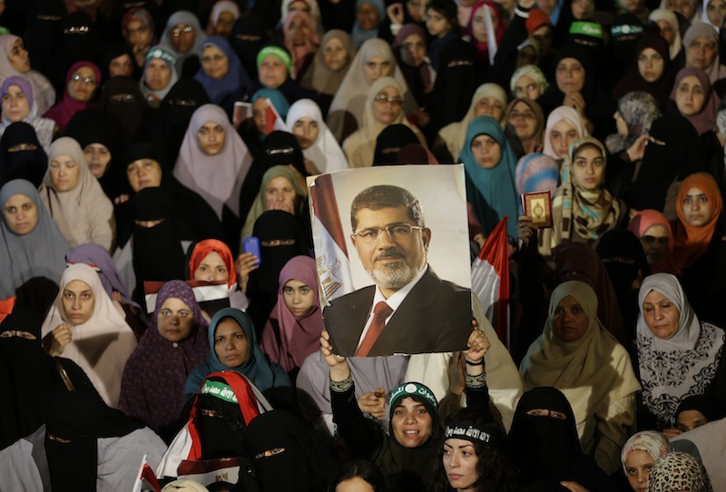 Supporters of the ousted Egypt's President Mohammed Morsi, hold his portrait during a demonstration after the Iftar prayer, evening meal when Muslims break their fast during the Islamic month of Ramadan, in Nasr City, Cairo, Egypt, Wednesday July 10, 2013. Egypt's military-backed government tightened a crackdown on the Muslim Brotherhood on Wednesday, ordering the arrest of its revered leader in a bid to choke off the group's campaign to reinstate President Mohammed Morsi one week after an army-led coup. (AP Photo/Hussein Malla)