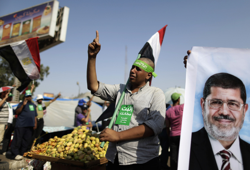 Supporters of Egypt's Islamist President Mohammed Morsi chant slogans during a rally in Nasser City, Cairo, Egypt, on Wednesday. The green card with Arabic reads, "stay where you are."