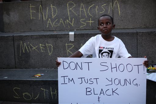 Abdul Kebbeh, 6, holds a sign at Westlake Park on Sunday, July 14, 2013 in downtown Seattle. Hundreds of people gathered at Westlake and marched to the United States Court House to protest the acquittal of George Zimmerman, the Florida man that shot and killed Trayvon Martin.